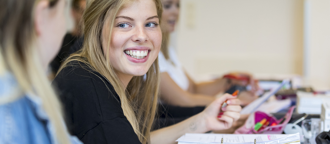 Junge Studentin schaut lächelnd in die Kamera